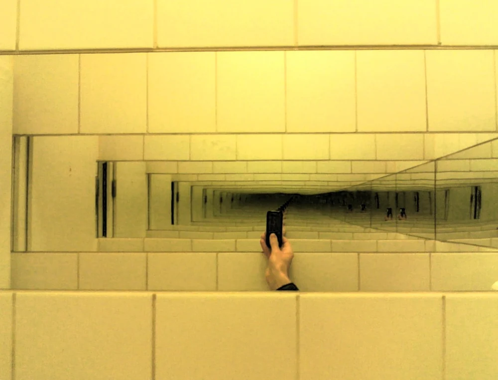 Bright lights repeating into the apparent depth of an infinity mirror.